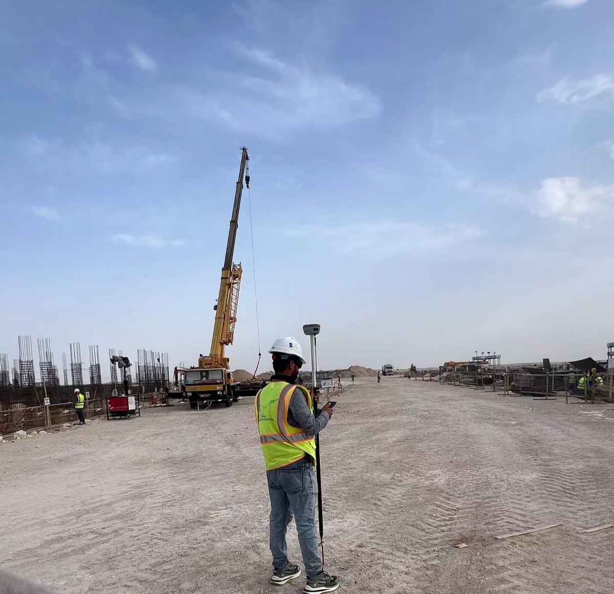 Surveyor using a Spherefix SP35 GNSS receiver at an active construction site in Oman